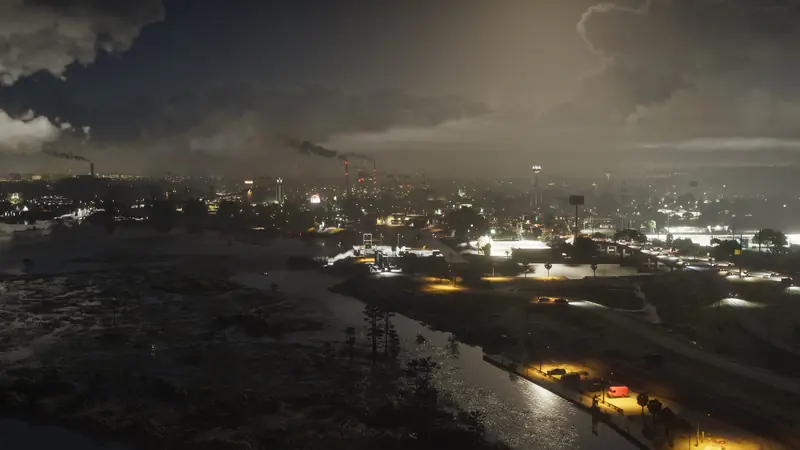 Ambrosia at night from the air, with refinery smoke drifting over the town lights