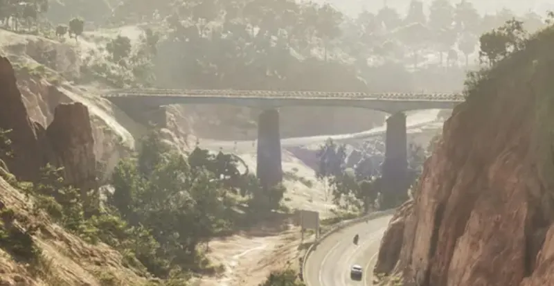 A train bridge spans a canyon above a highway in Kelly County
