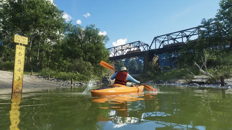 A kayaker paddles a river under an old railway bridge