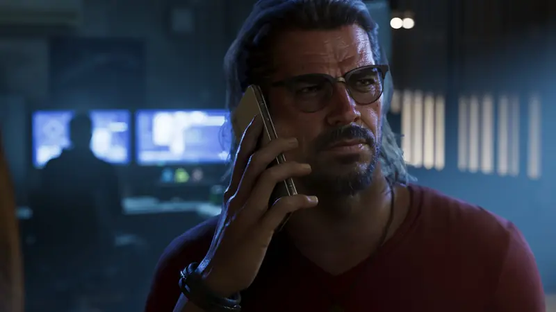 Raul Bautista talks on the phone in a dark room full of screens
