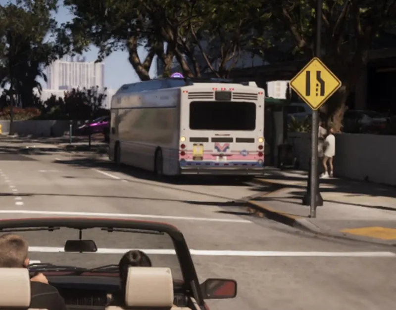 A city bus pulls up at a stop on the Rialto Causeway, seen from a convertible