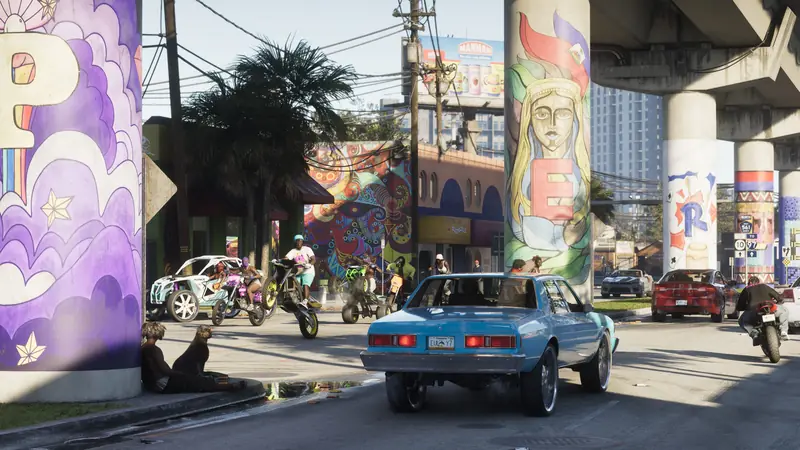 Murals cover the pillars of an overpass as cars and dirt bikes pass beneath